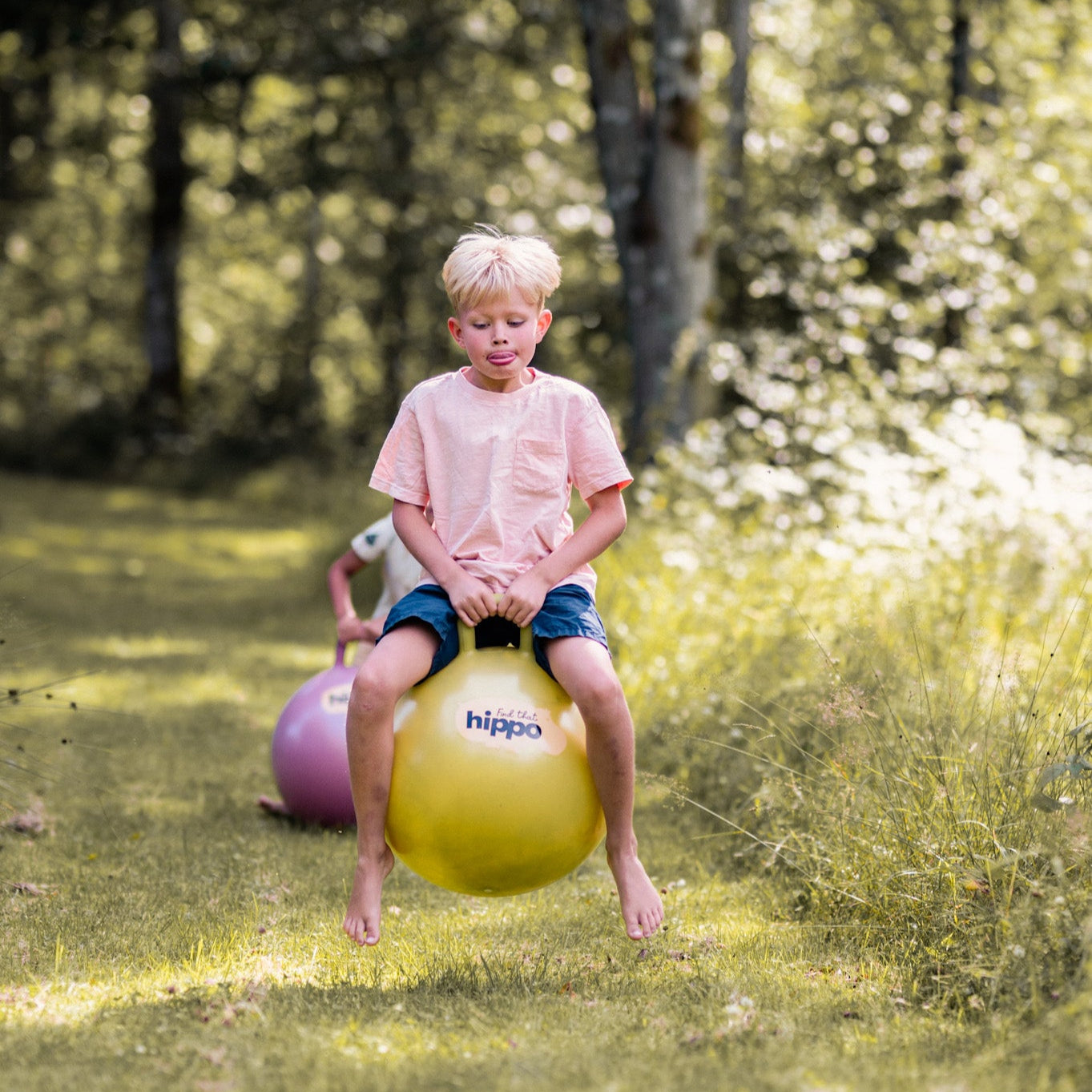 Child sitting on yellow bouncing ball in a forest setting – Find That Hippo