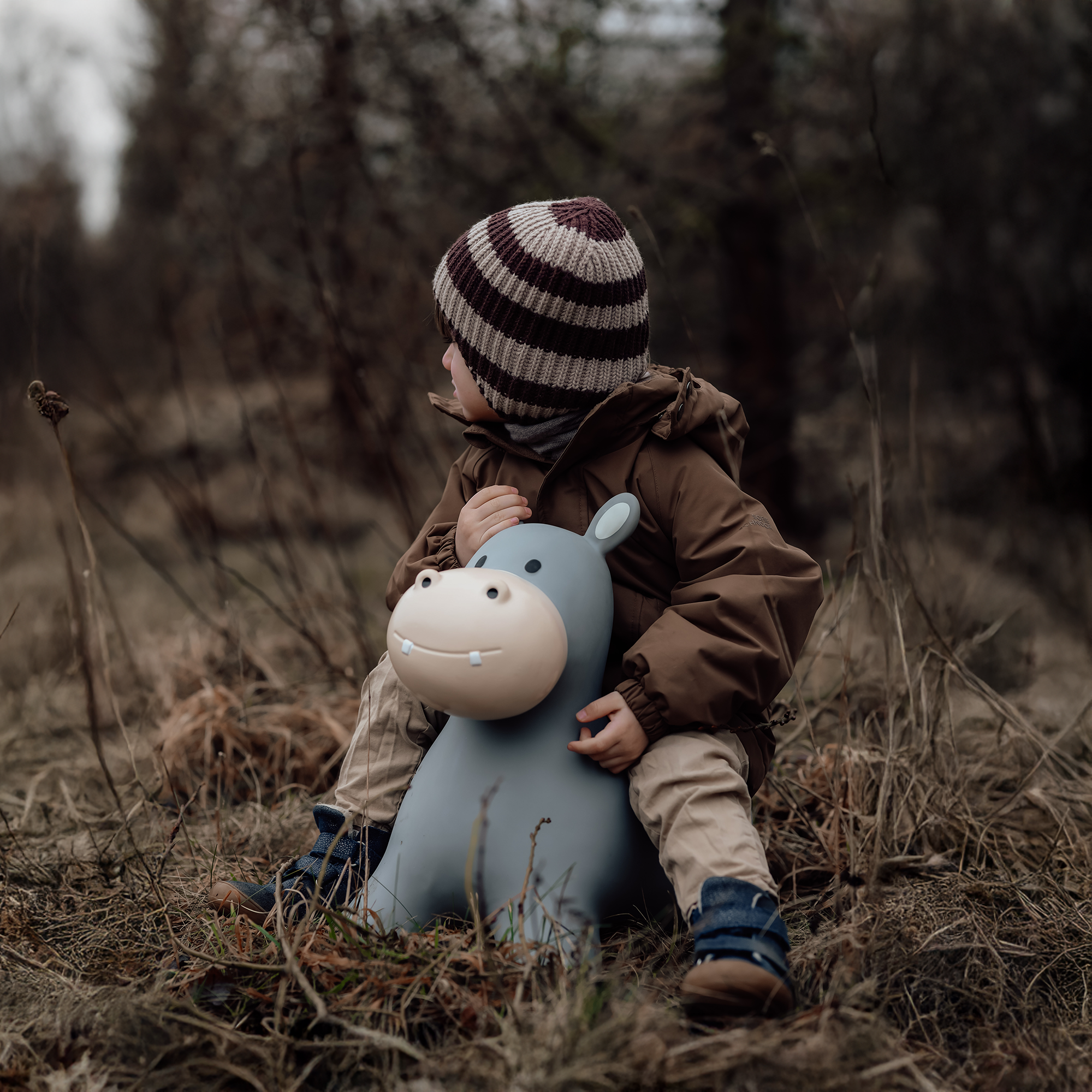 Child resting head on Holger the bouncing hippo toy in the woods – Find That Hippo