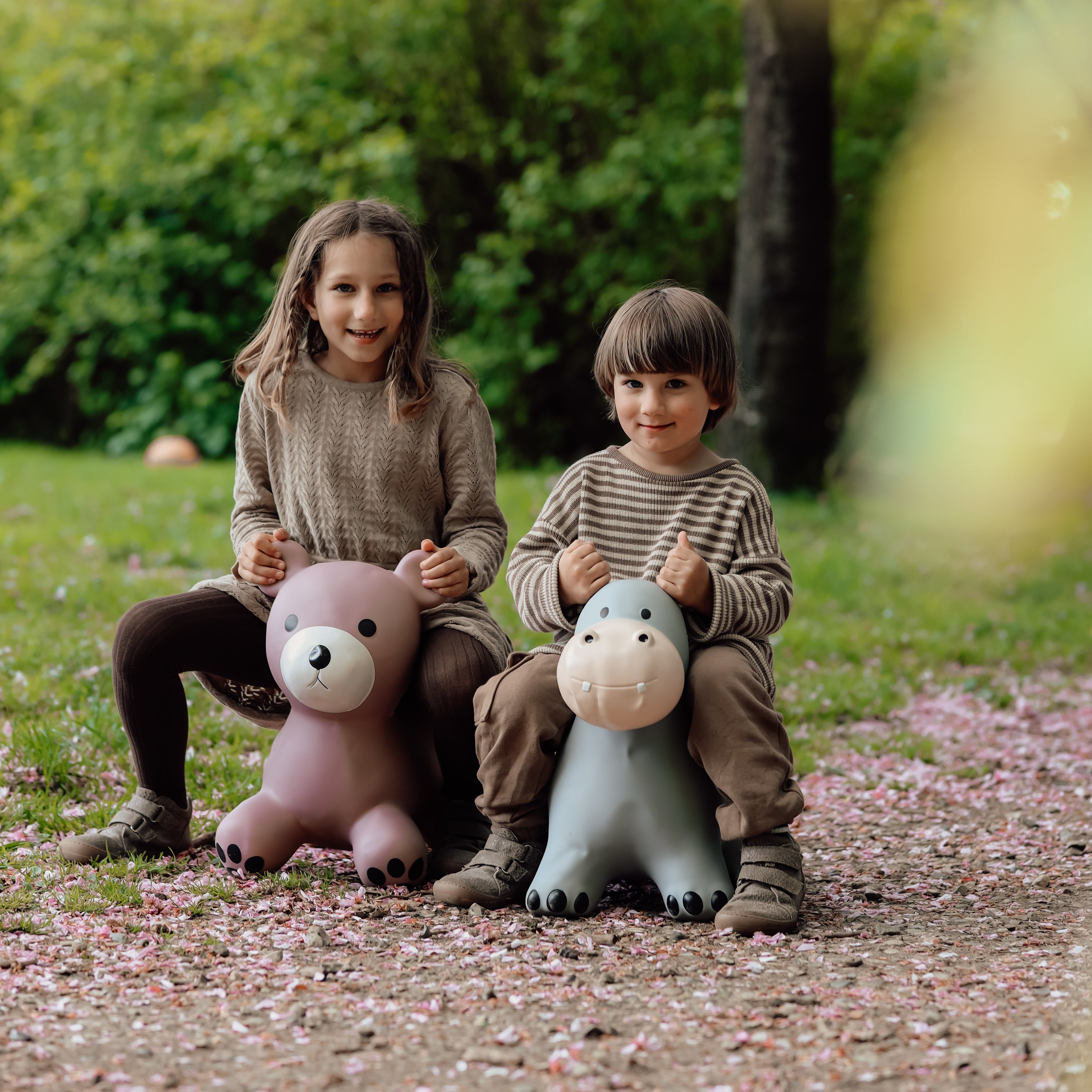 Two children sitting on bouncing toys including Holger the hippo in a forest setting – Find That Hippo